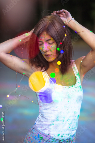 Lovely brunette woman covered with Holi dry powder and holding garland