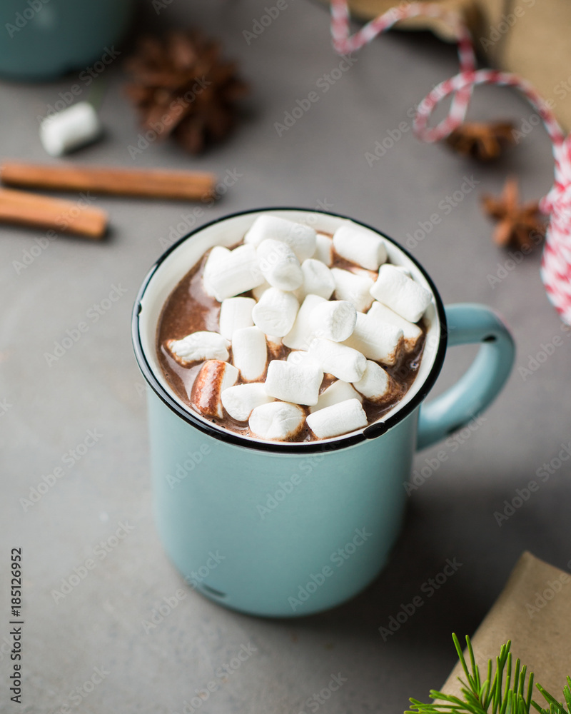 Mug of hot chocolate with marshmallow and cinnamon on a gray concrete background with a Christmas tree, gifts. and red-white string (twine). Winter xmas holidays concept. Festive mood. Mug of hot chocolate with marshmallow and cinnamon on a gray concrete background with a Christmas tree, gifts. and red-white string (twine). Winter xmas holidays concept. Festive mood.