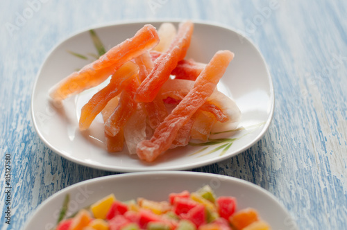 Candied papaya in a white plate on a wooden background