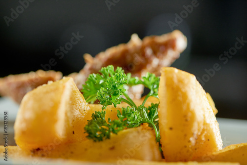 Little restaurant bowl served with goldy fried potato slices, thin roasted sausage and decorated with fresh parsley leaves. Looks very delicious and nourisihing. photo