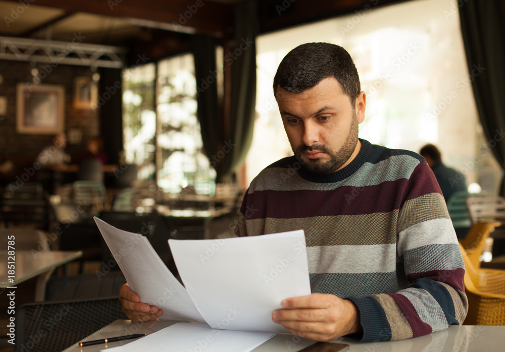 Stressed young man reading a document Stressed young man reading a document