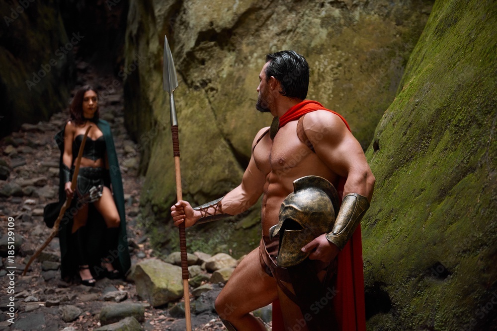 Muscular Spartan warrior with stunning ripped strong body walking away from  his wife looking at her with love goodbye relationships love people  medieval couples romance affectionate. Stock Photo