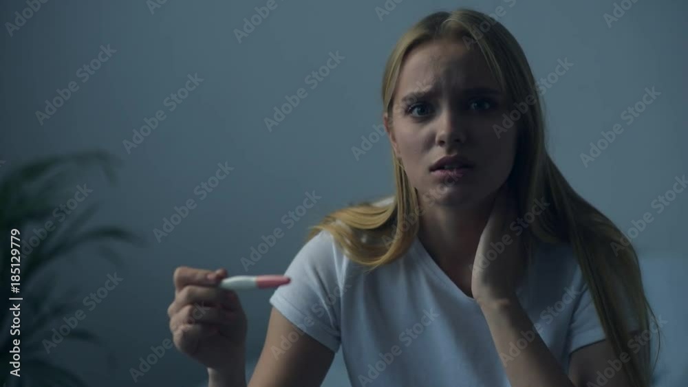 Complicated situation. Close up of depressed girl holding pregnancy test while feeling nervous and downhearted Complicated situation. Close up of depressed girl holding pregnancy test while feeling nervous and downhearted
