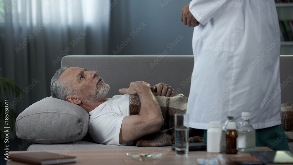 Obraz premium Grandfather lying on couch and complaining doctor of heart pain, healthcare