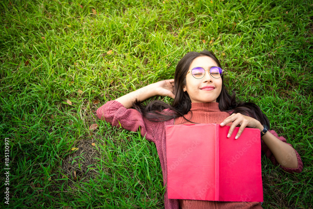 Portrait of high school girl lay down and read a book in park, education concept Portrait of high school girl lay down and read a book in park, education concept