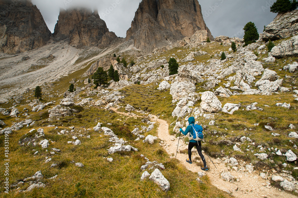 Fototapeta premium A single hiker walking up a beautiful mountain trail in the Dolomite mountains 