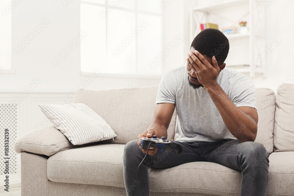 Unhappy young man at home playing video games and loses