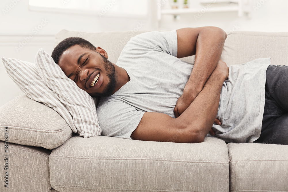 Handsome young african-american man suffering from stomachache