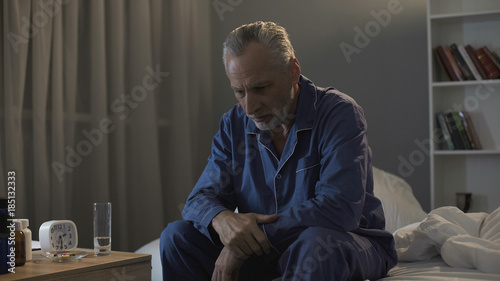 Depressed senior person sitting in bed and suffering from insomnia, health