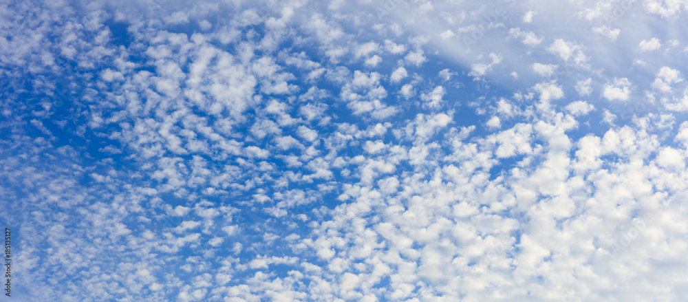 Blue sky with white scattered clouds background.