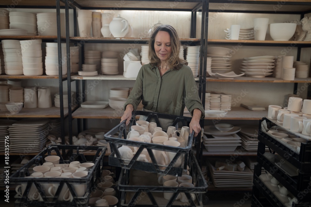 Female potter holding cups in crate Female potter holding cups in crate