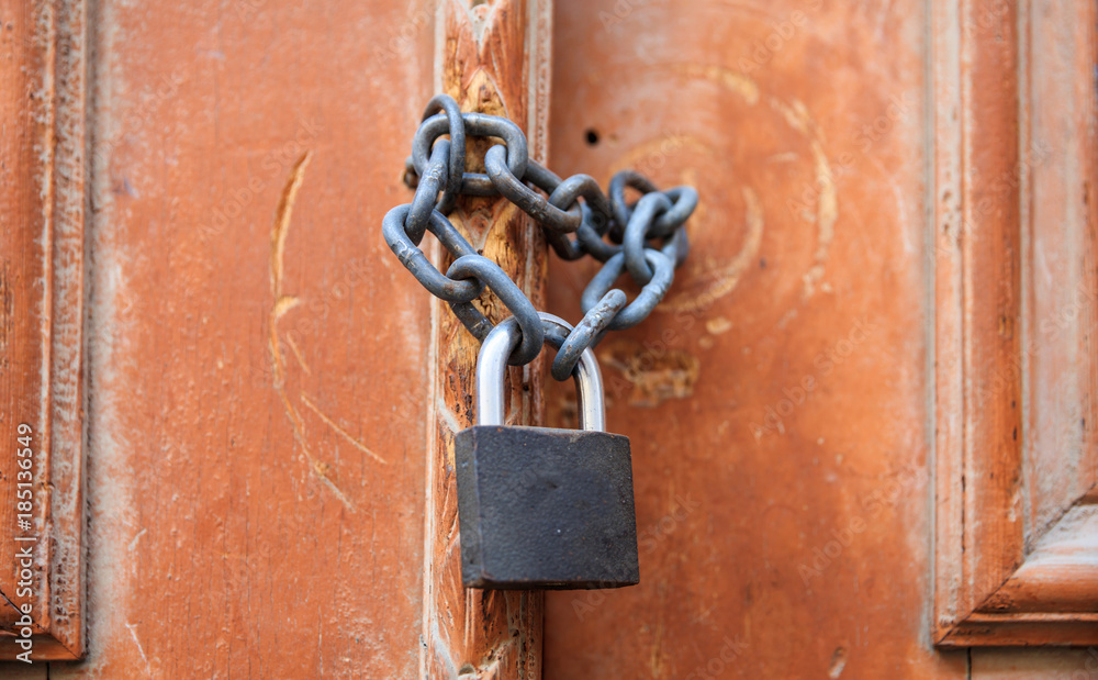 Padlock with chain blocking the entrance. Wooden door, close up view. Padlock with chain blocking the entrance. Wooden door, close up view.