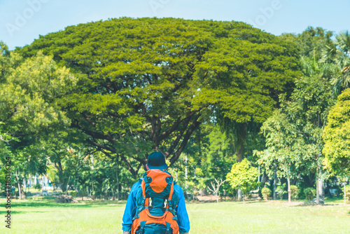 Man with a backpack standing in a park. Backpacker in nature