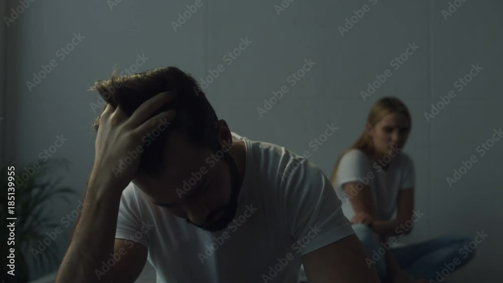 Weak relationships. Young couple sitting on the bed while feeling uncomfortable with each other and expressing sadness