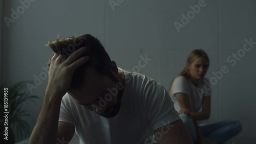 Weak relationships. Young couple sitting on the bed while feeling uncomfortable with each other and expressing sadness