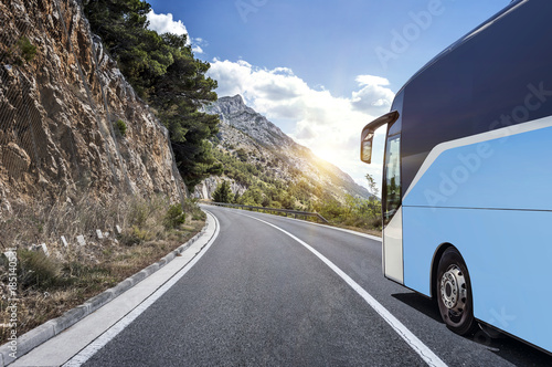 Tourist bus rushes along the country high-speed highway against the background of a mountain landscape.