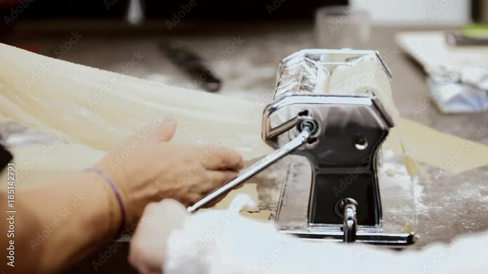 children with their grandmother make sheets of pasta for lasagna. homemade pasta for lasagna on a home machine for lasagna. Making Lasagna sheets at home, flattened dough in pasta machine close-up children with their grandmother make sheets of pasta for lasagna. homemade pasta for lasagna on a home machine for lasagna. Making Lasagna sheets at home, flattened dough in pasta machine close-up