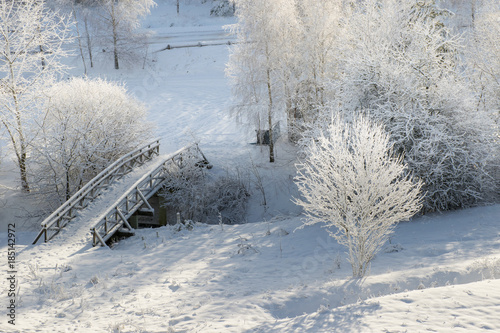 Fototapeta Naklejka Na Ścianę i Meble -  Snowy, wooden bridge in a winter day. View from above.