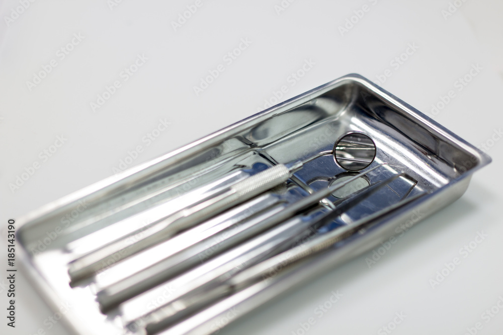 Dental instruments in a metal tray on an isolated white background Dental instruments in a metal tray on an isolated white background