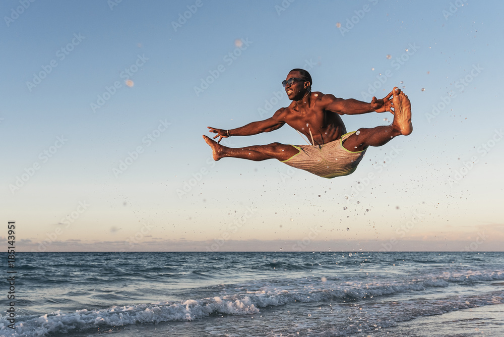 Young man jumping into the beach.