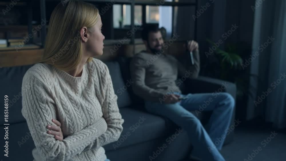 Why so sad. Close up of young frustrated girl being nervous while her boyfriend sitting on the sofa and expressing optimism