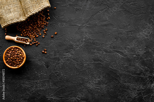 Fresh roasted coffee beans in bowl and scoop on black table top view copyspace