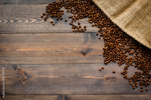Roasted beans near canvas on dark wooden table top view copyspace. Coffee background.