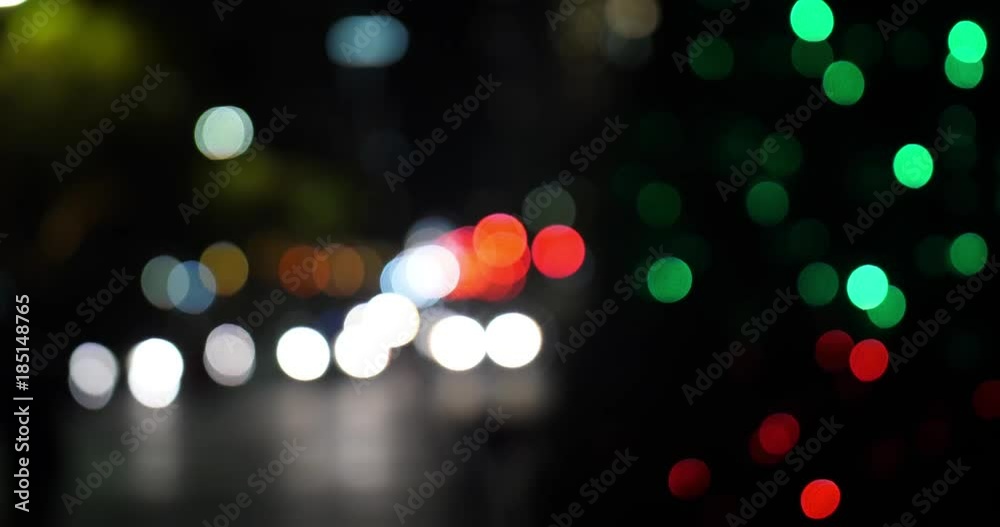 Out of focus Christmas tree lights with bokeh traffic in the distance.
