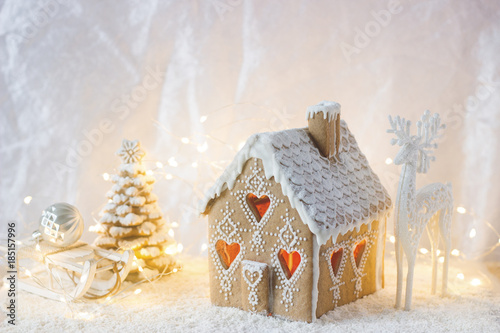 Gingerbread house, Christmas trees and a figure of a deer on a luminous background. Bokeh effect.
