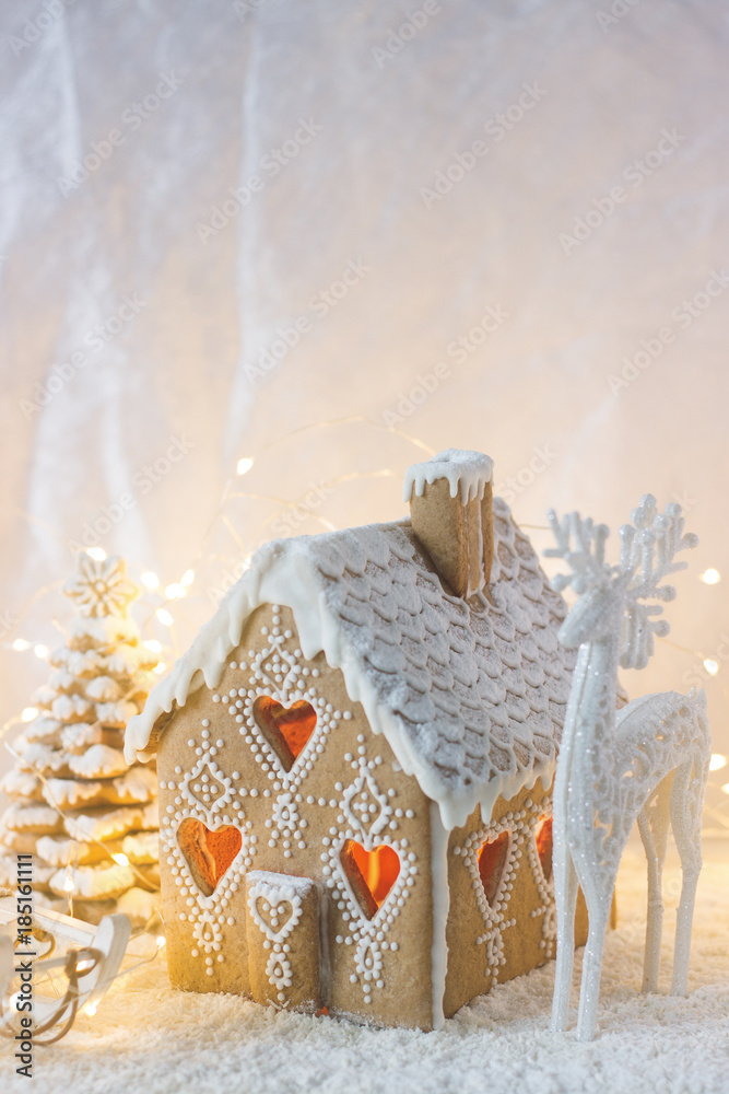 Gingerbread house, Christmas trees and a figure of a deer on a luminous background. Bokeh effect.