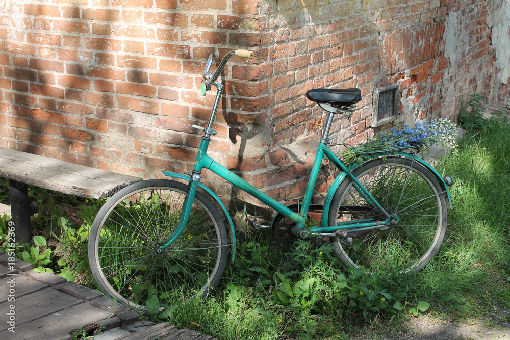 old bicycle with flowers near the old stone wall waiting for the owner old bicycle with flowers near the old stone wall waiting for the owner