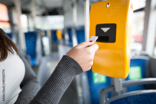 Young woman hand inserts the bus ticket into the validator, validating and ticking
