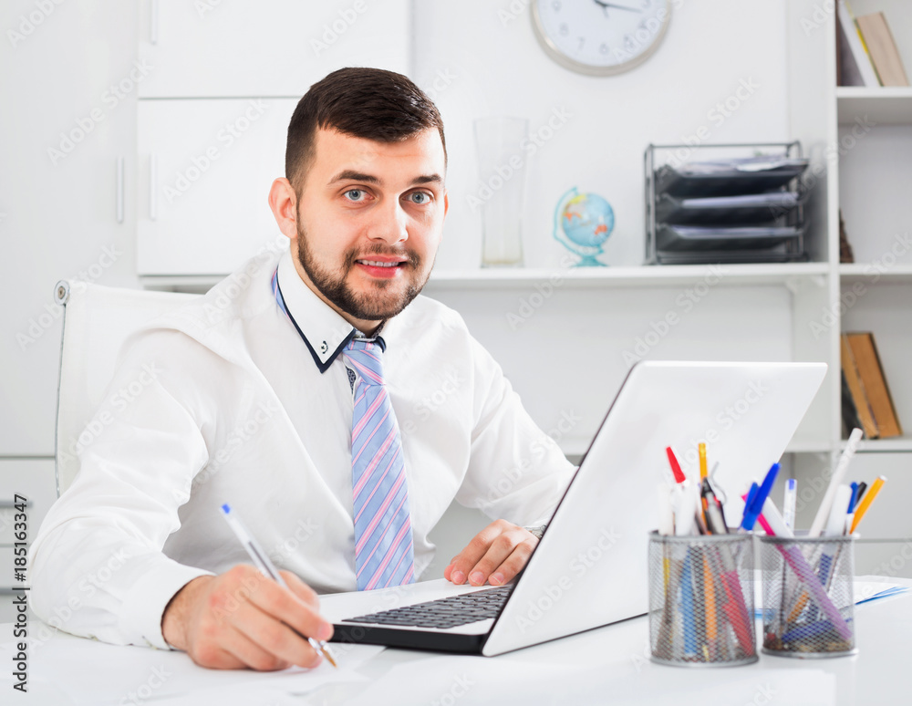 Young male worker working productively on project in office