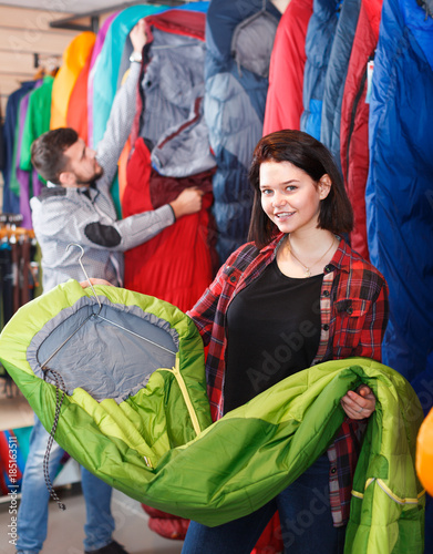 Laughing female customer examining sleeping bags