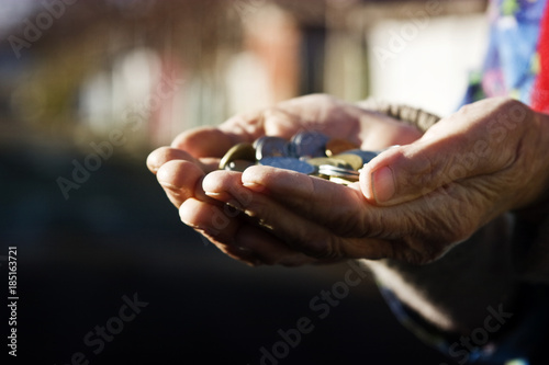An old grandmother holds several coins in wrinkled hands