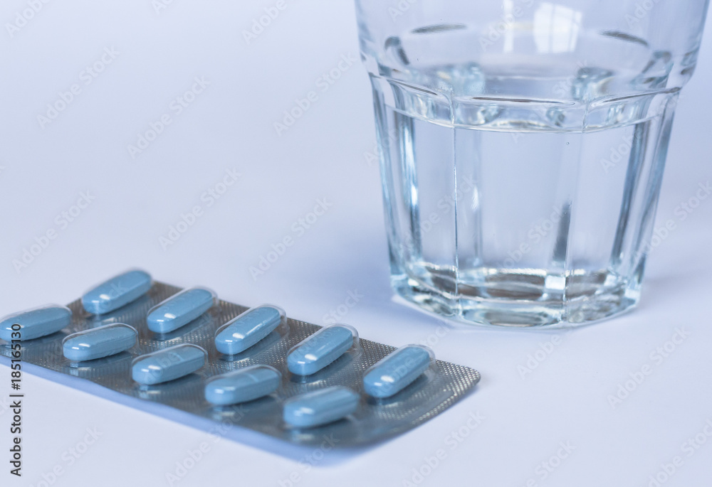 Glass of water and blue pills. Glass of water and blue pills.