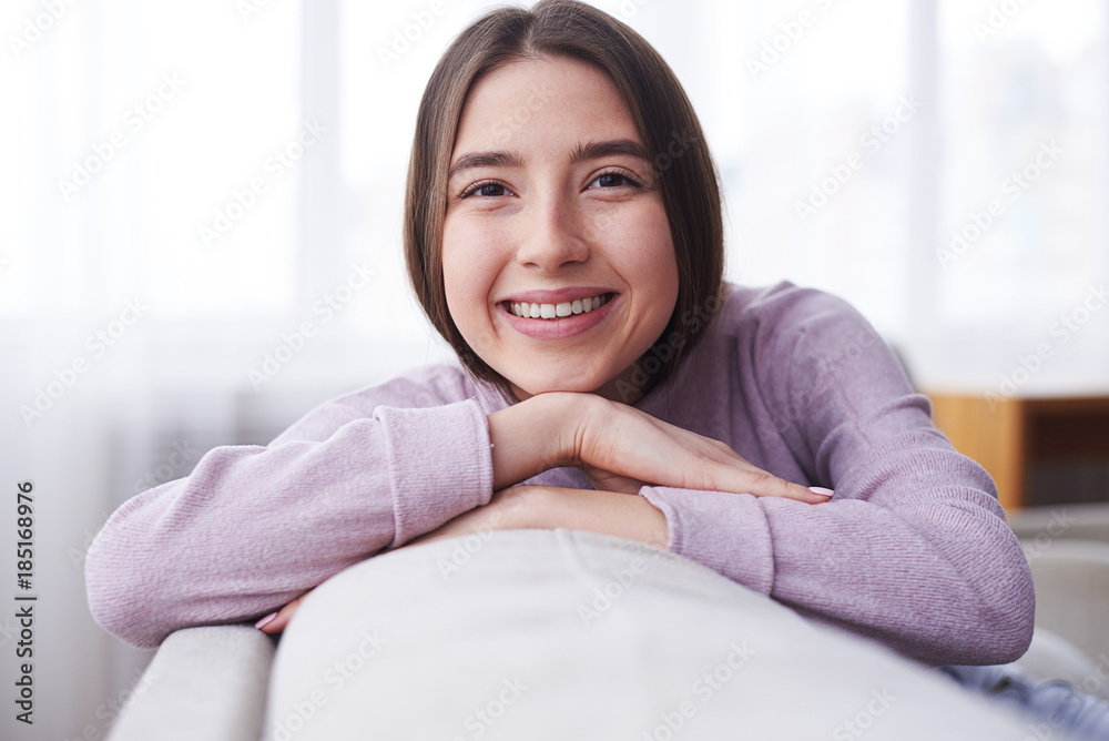 Happy girl wearing cozy sweater leaning on sofa Happy girl wearing cozy sweater leaning on sofa