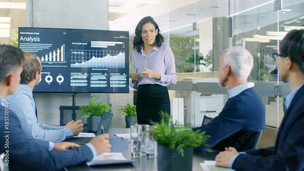 Beautiful Businesswoman Gives Report/ Presentation to Her Business Colleagues in the Conference Room, She Shows Graphics, Pie Charts and Company's Growth on the Wall TV.  RED EPIC-W 8K Camera.