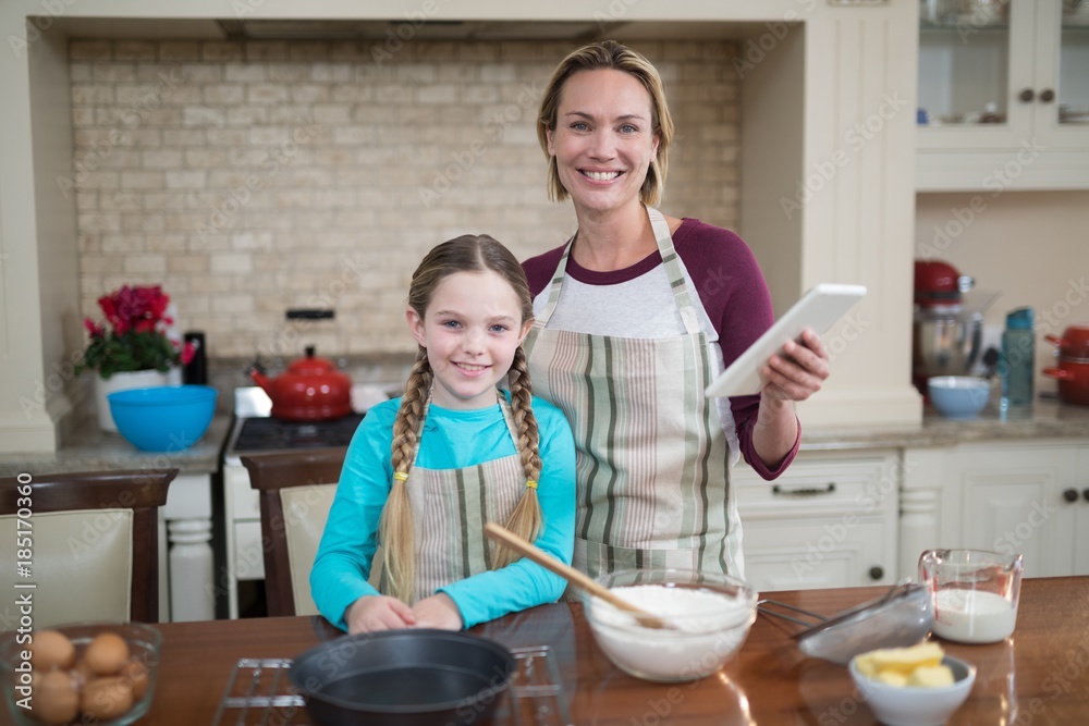 Smiling mother and daughter using digital tablet while preparing Smiling mother and daughter using digital tablet while preparing