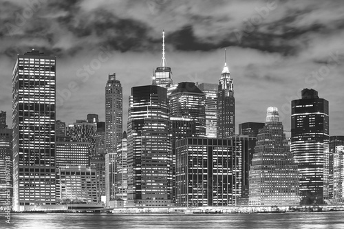 Black and white picture of New York City illuminated skyscrapers at night, USA.