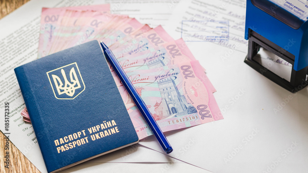 International Ukrainian passport with hryvnias on document background. Ukrainian money, documents, stamp and passport. International Ukrainian passport with hryvnias on document background. Ukrainian money, documents, stamp and passport.