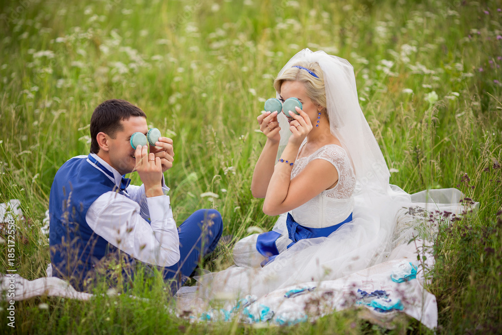 Wedding couple having fun with blue macaroons. Joyful and happy bride and groom. Marriage concept Wedding couple having fun with blue macaroons. Joyful and happy bride and groom. Marriage concept