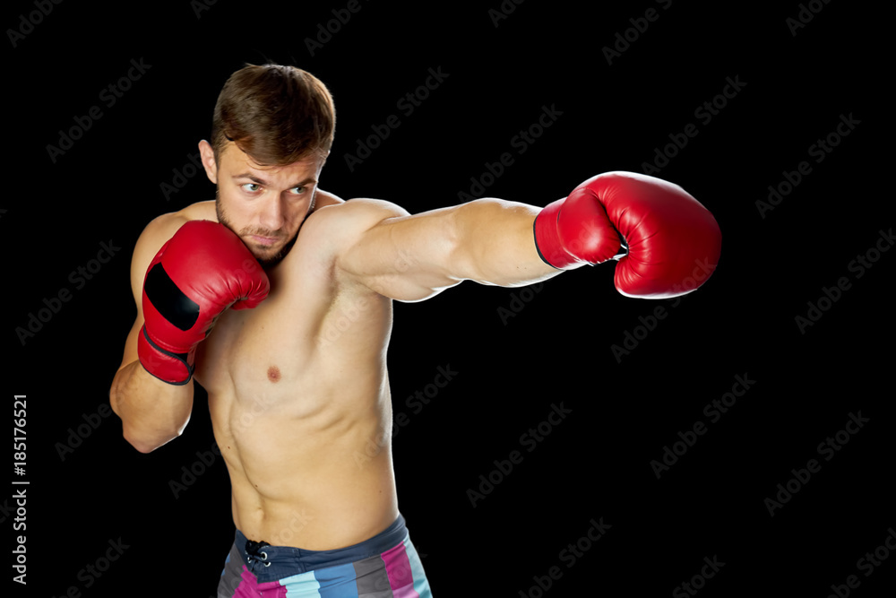 Young boxer in red gloves. Athletic man throwing a pushing punch. Boxing classes concept.