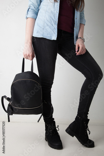 Women's legs in the city street. Blue cropped denim jeans, black high heel sandals and black backpack. Trendy stylish casual outfit.