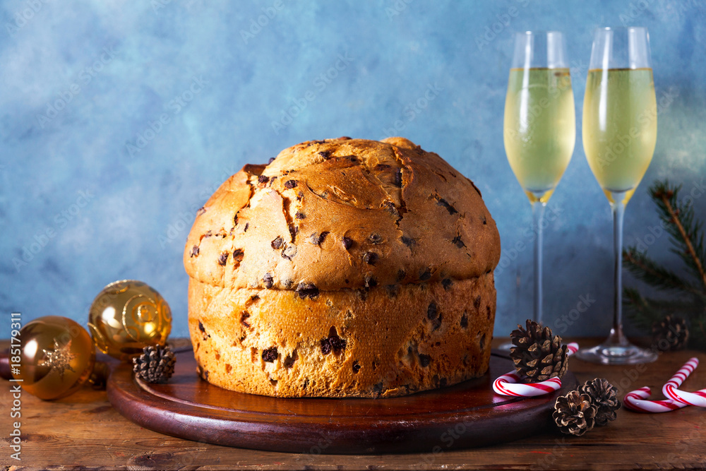Italian festive bread panetton on a table decorated for Christmas. and two glasses of champagne. New Year's traditional dessert Italian festive bread panetton on a table decorated for Christmas. and two glasses of champagne. New Year's traditional dessert
