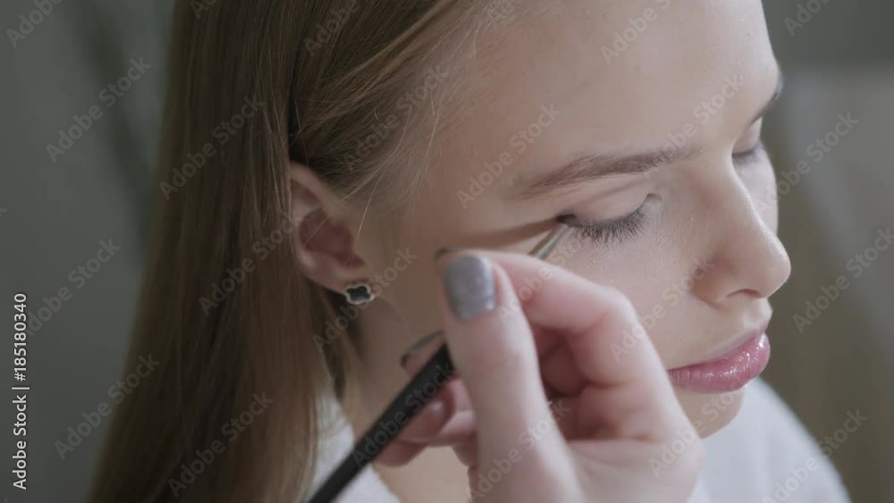 Paint eyes mascara. Makeup artist creating beautiful makeup for blondes model. Beauty and Spa centre concept Paint eyes mascara. Makeup artist creating beautiful makeup for blondes model. Beauty and Spa centre concept