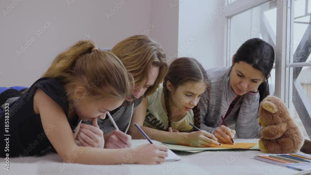 Young family are drawing pictures together relaxing on the floor Young family are drawing pictures together relaxing on the floor