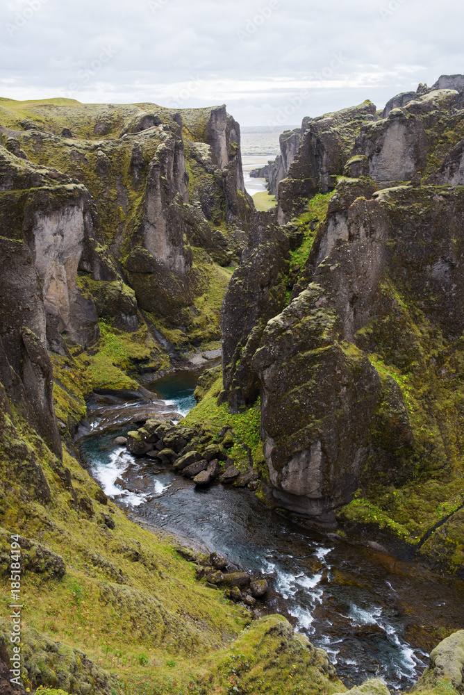 A green, moss covered canyon with a river running through in Iceland. 