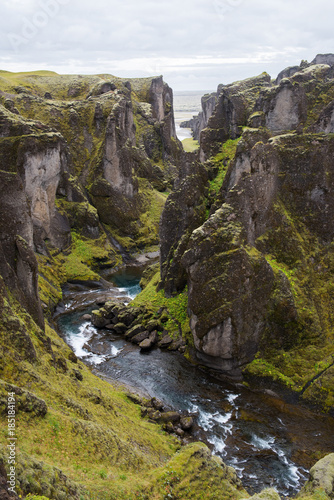 A green, moss covered canyon with a river running through in Iceland. 