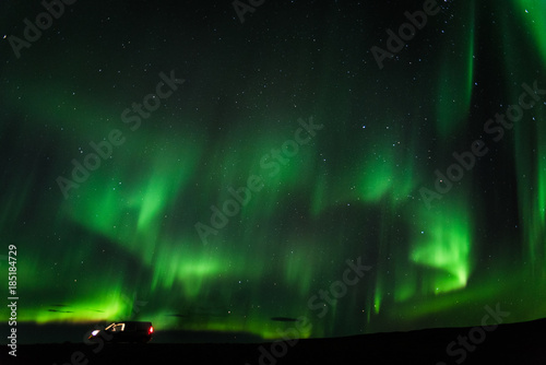 Green northern lights in Iceland with a camper van on the ground. 